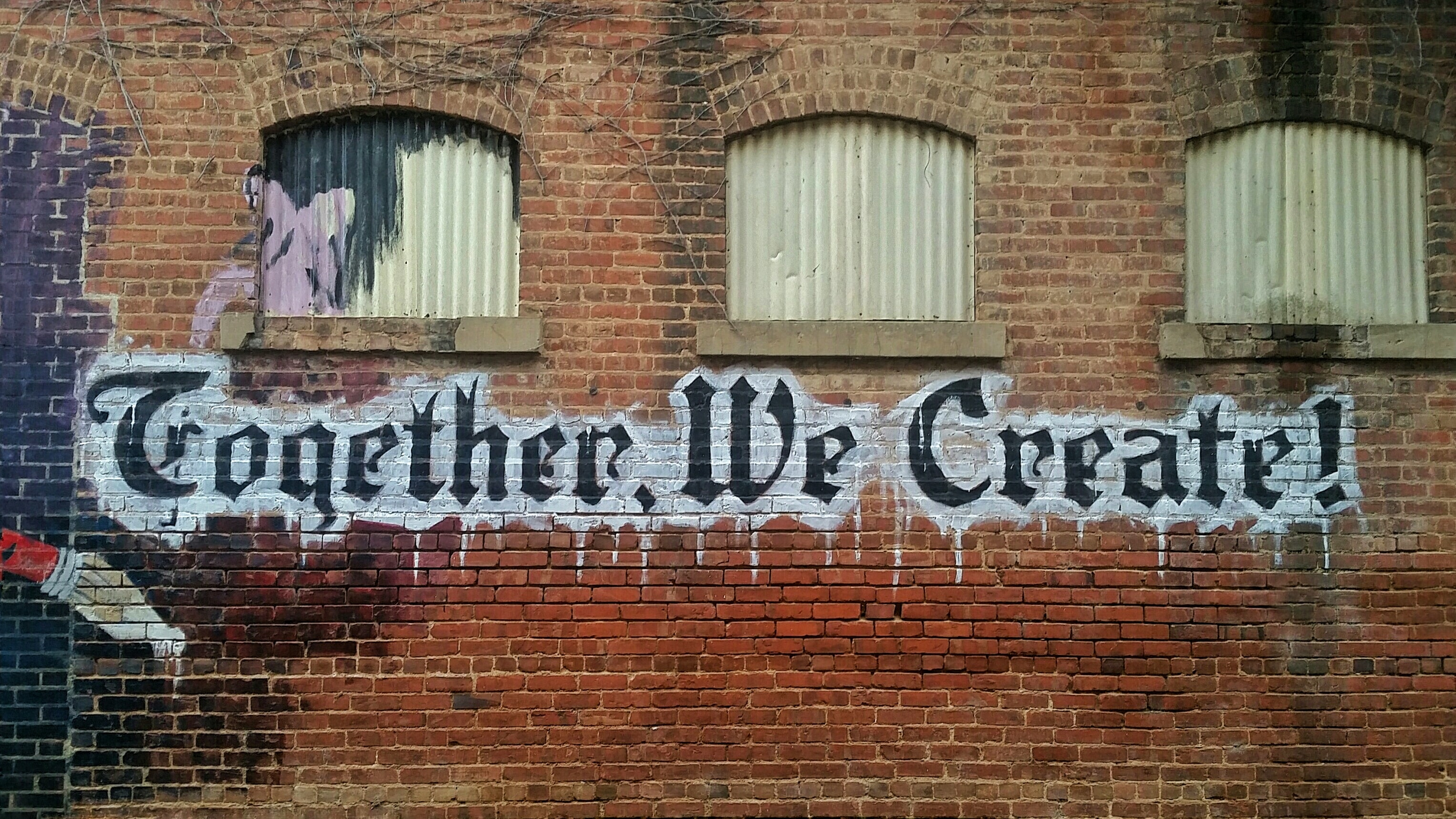 Brick building with "Together we Create" written as graffiti